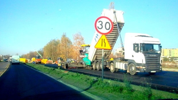 Kolejka ciężarówek z asfaltem oczekuje na rozładunek.