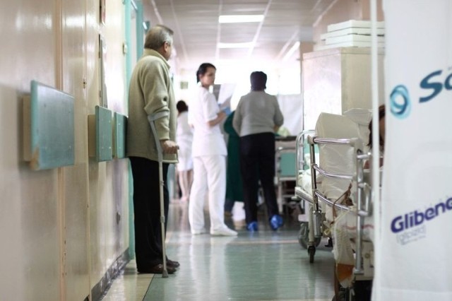 To fragment korytarza interny I w szpitalu na Józefowie. Chorzy leżą na dostawkach, a pomiędzy nimi jeżdżą wózki z jedzeniem, chodzi personel i odwiedzający.  