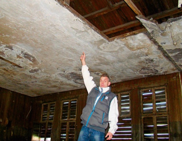 Mirosław Ganobis pokazuje połamane stropy i poszycie dachu w dawnej kantynie esesmanów