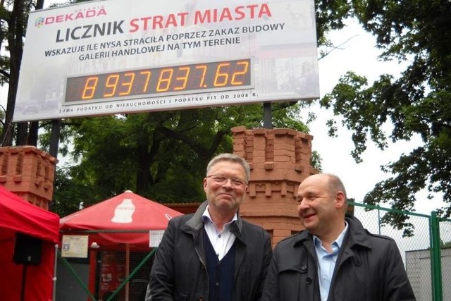 Aleksander Walczak i Ryszard Urbański z firmy Dekada na tle licznika strat miasta.
