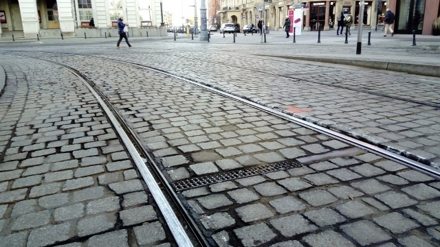 Miejsca w których widać naruszoną kostkę brukową przy torach tramwajowych