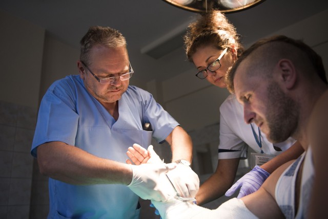 Dostęp do specjalistów jest coraz bardziej ograniczony. Lekarz chirurg Cezary Jarek sciąga gips z ręki pacjenta.