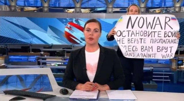 Zdjęcie pokazuje redaktorkę rosyjskiego Channel One, Marinę Owsiannikową. Kobieta trzymająca plakat z napisem „Zatrzymaj wojnę. Nie wierz propagandzie. Okłamują cię” weszła na wizję podczas wiadomości Jekateriny Andrejewej, najchętniej oglądanych wieczornych wiadomości w Rosji. Miało to miejsce w Moskwie 14 marca 2022 r.