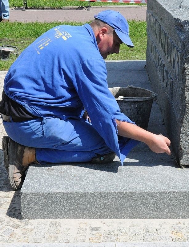 Pracownik Zakładu Kamieniarskiego Furmanek w Daleszycach mocuje cokół pomnika.