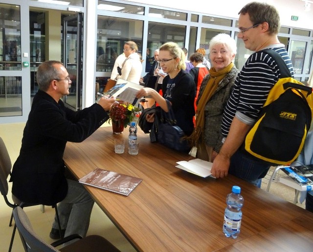 Wojciech Jagielski rozdaje autografy na swoich książkach.