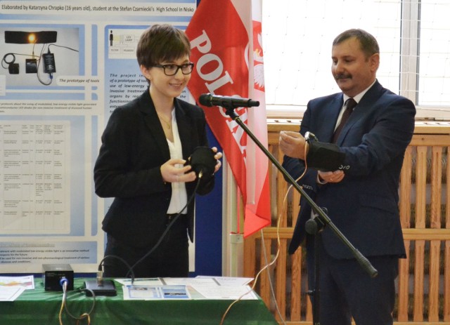 Katarzyna Chrapko prezentuje urządzenie do leczenia światłem na dyrektorze liceum Jerzym Stelmachu