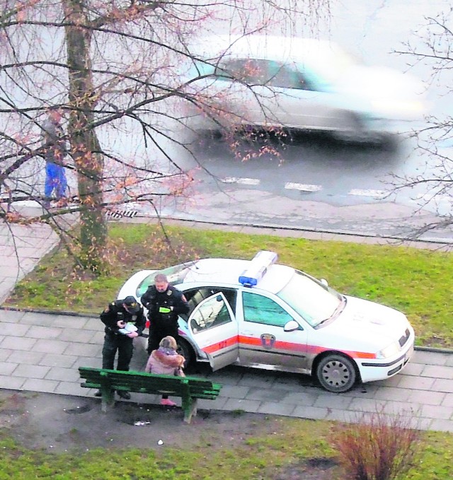 Strażnicy legitymują bosą kobietę odpoczywającą na ławce.