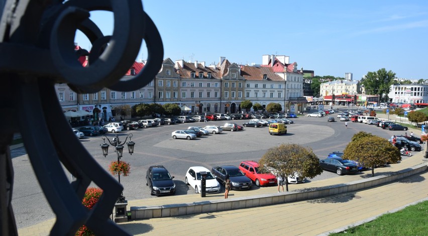 Plac Zamkowy w upalne dni zalany jest słońcem. Cień rzucają...