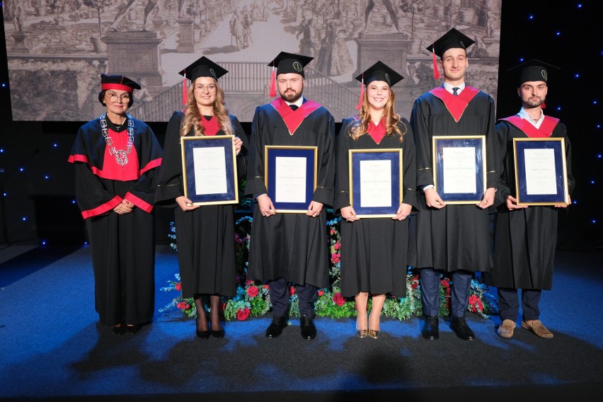 Absolwenci pozują do zdjęć z dyplomami