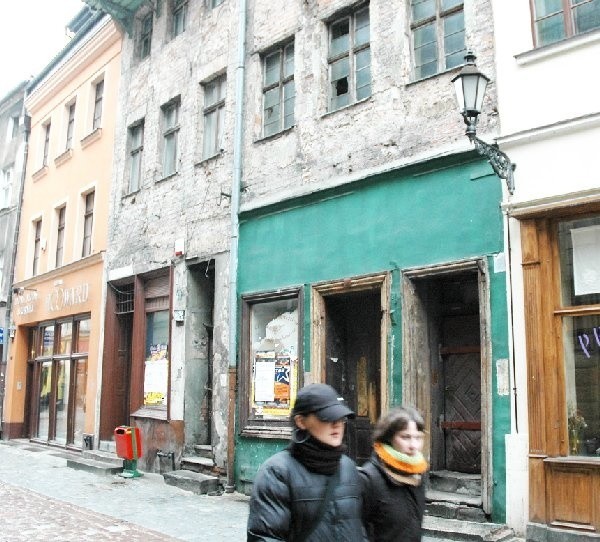 Ulica Szewska. Pomiędzy pięknie  odnowionymi budynkami dwie rudery. Z lewej  (numer 15), którą Prus-Grobelski kupił w 1999  roku od miasta. Z prawej ta, w której jest  zameldowany.