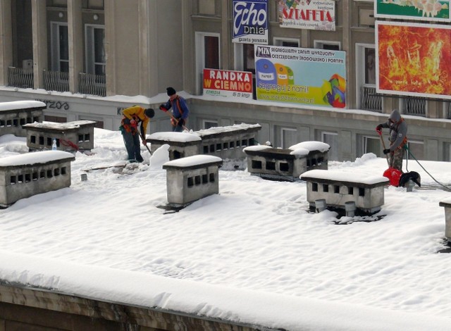 Ekipa pracowników usuwających śnieg z dachu z bloku przy ulicy 1 Sierpnia.