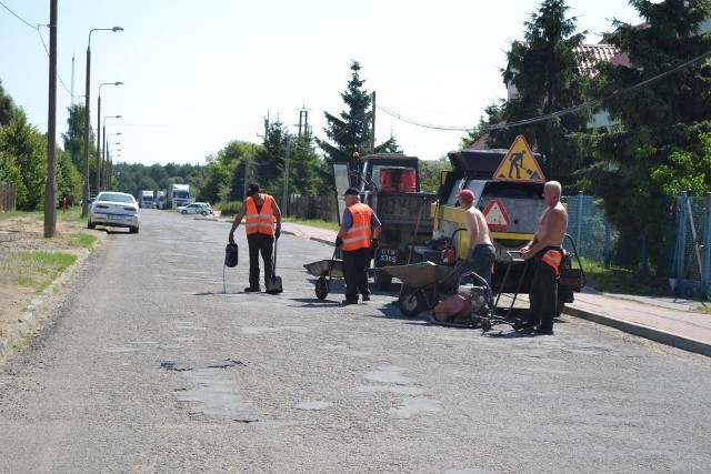 Ekipa ZGKiM w dziury leje z konewki masę bitumiczną i zasypuje drobnymi kamyczkami.