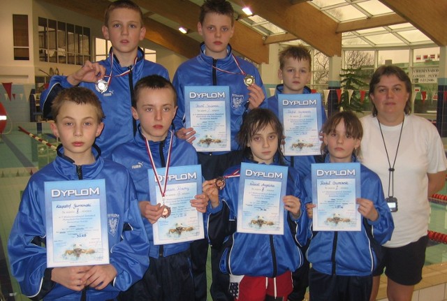 Młodzi pływacy z dyplomami i medalami.