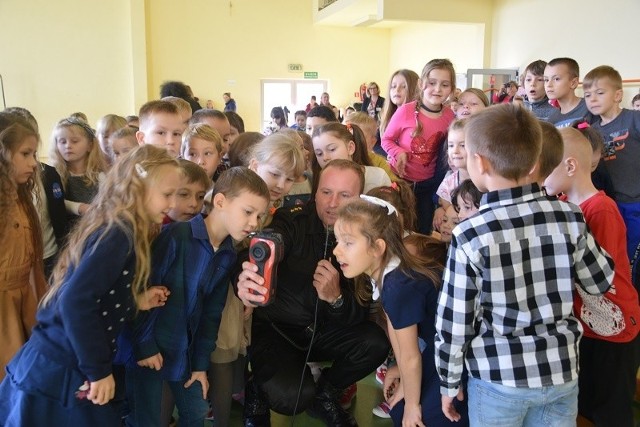Kapitan Mateusz Tarka, z Komendy Powiatowej Państwowej Straży Pożarnej pokazuje dzieciom kamerę termowizyjną. Pierwszaki były zachwycone!