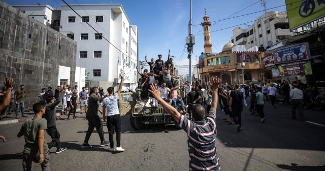 Palestyńczycy jadący izraelskim wojskowym jeepem ulicami Gazy podczas szturmu izraelskich osiedli