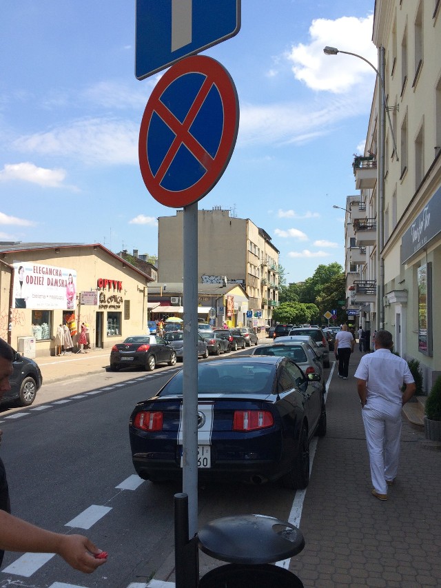 Ul. Jasna. Znak pionowy - na słupku - zakazuje w tym miejscu parkowania, znak poziomy - na jezdni - dopuszcza parkowanie