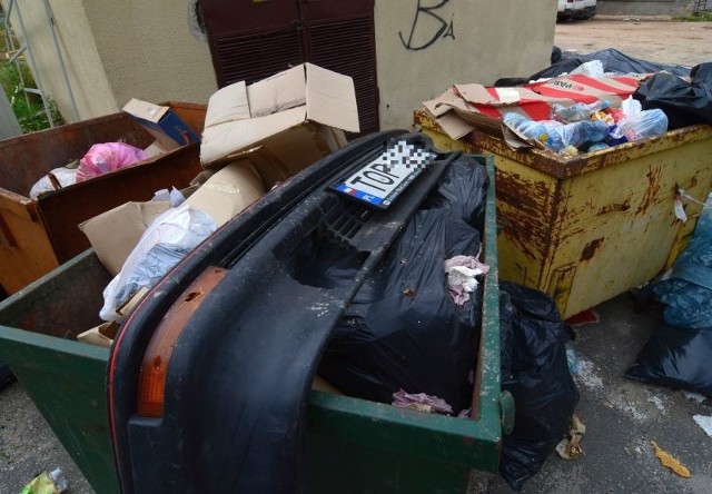 Zderzak z tablicą rejestracyjną ktoś wyrzucił na śmietnik przy domu kultury w Opatowie.