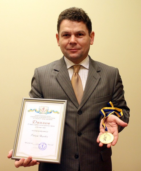 Sędzia Robert Pelewicz prezentuje dyplom i medal, którym został uhonorowany przez ukraińską fundację.