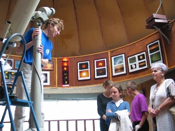 Pracownik planetarium, Bartosz Dąbrowki (przy  teleskopie) zachęca uczestników do własnych  obserwacji nieba.