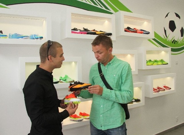 Wojciech Jagodziński (z lewej), właściciel sklepu Young Sport w Kielcach pokazuje klientowi obuwie piłkarskie dla dzieci.