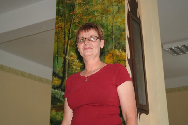Zofia Pawlikowska, żona sołtysa, jest zadowolona z pracy malarza, który namalował las głażewski na kominku