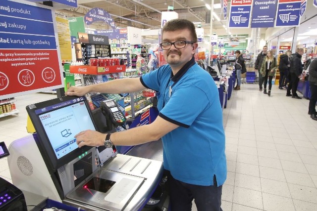 Sławomir Marek z Tesco Extra w Kielcach nadzoruje pracę kas samoobsługowych, pomaga klientom w korzystaniu z nich.