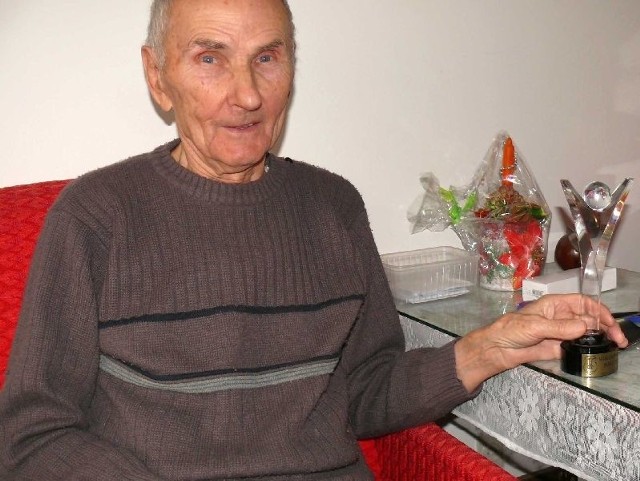 Pan Aleksander w swoim domu z kryształową statuetką Wolontariusza Roku.