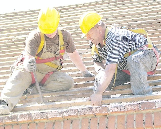 Artur Wiśniewski (z prawej) i Marcin Kwiatkowski, pracownicy grudziądzkiej firmy "Budrex&#8221; wymieniają dach na budynku Zielonej Szkoły w Orłowie