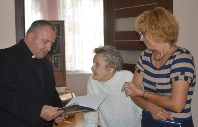 Upominki przekazuje jubilatce ks. Jan Zwierzchowski. Z prawej córka, Teresa Nowak