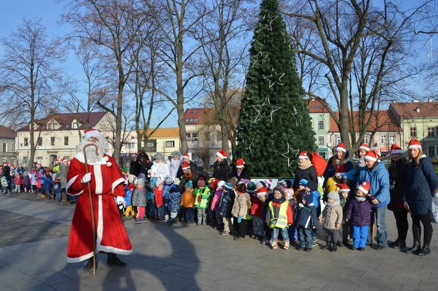 Orszak z Mikołajem, aniołami oraz diabłem prowadzącym dzieci z kina do  przedszkola, zatrzymał się na Rynku pod choinką