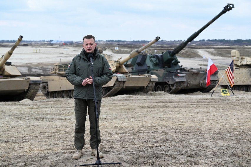 Minister Mariusz Błaszczak na tle czołgów Abrams