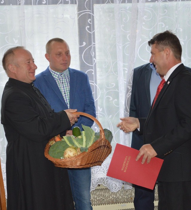 Prezes Zbigniew Orzechowski (z prawej) obdarował gości warzywami. Na zdjęciu podarunek odbiera ks. Krzysztof Olszewski.