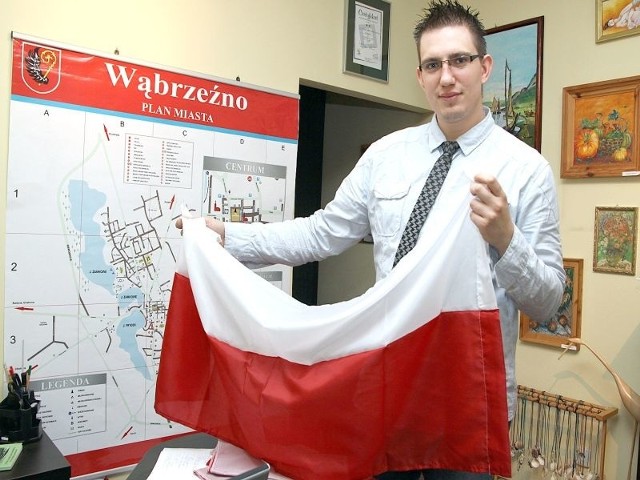 Dawid Marchlewicz prezentuje jedną z flag dostępnych w Miejskim Punkcie Informacji