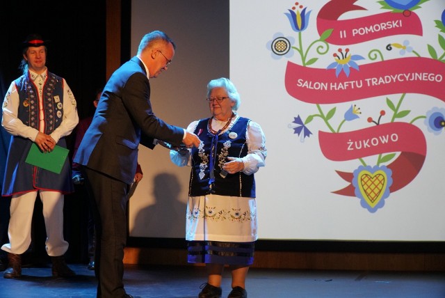 Podczas II Salonu Haftu Tradycyjnego w Żukowie Jarosław Sellin, wiceminister kultury i dziedzictwa narodowego uhonorował medalem "Gloria Artis" Marię Płotkę, zasłużoną żukowską hafciarkę.