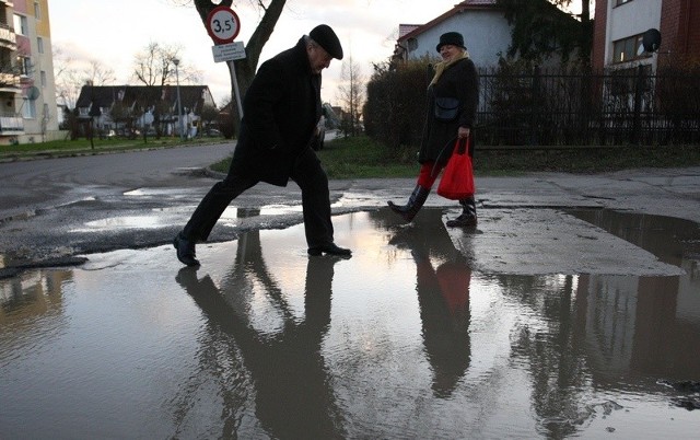 Pan Janusz pokonuje ogromną kałużę na swoim osiedlu. 