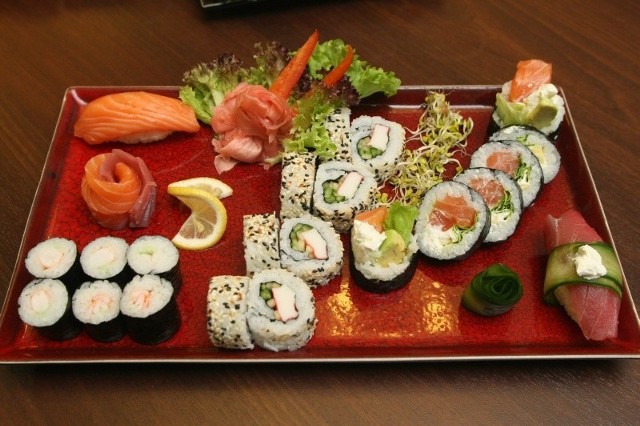 Sushi podano do degustacji ułożone w charakterystyczny sposób z dodatkiem marynowanego imbiru, kiełków roślin i sosu sojowego.