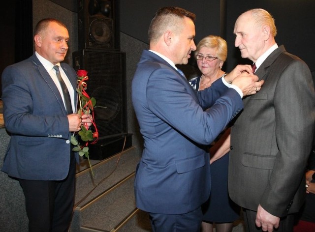 Medalami dekoruje długoletnich małżonków burmistrz Włoszczowy Grzegorz Dziubek; z tyłu stoi jego zastępca Sławomir Owczarek. 