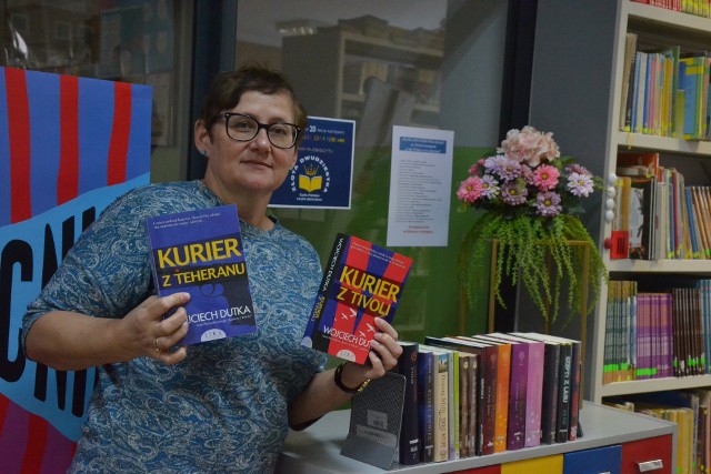 dyrektor Katarzyna Kwiecińska w bibliotece z książką, o której rozmawiano podczas spotkania Dyskusyjnego Klubu Książki