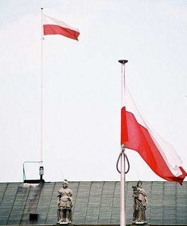 Flagi Polski przed i na Pałacu Prezydenckim w Warszawie