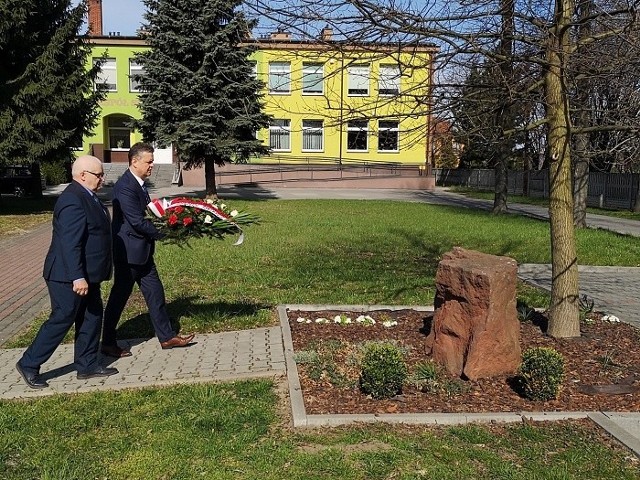 Burmistrz Sławomir Kowalczyk i Przewodniczący Rady Miejskiej Henryk Kryca składają kwiaty pod Dębem Pamięci na placu przy Zespole Szkolno-Przedszkolnym w Opatowcu.