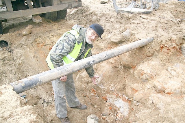 Archeolog Maciej Trzciński pokazuje fragmenty odkopanych murów miejskich