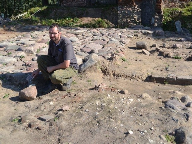 Archeolog Robert Grochowski na odkrytej drodze brukowej z czasów krzyżackich