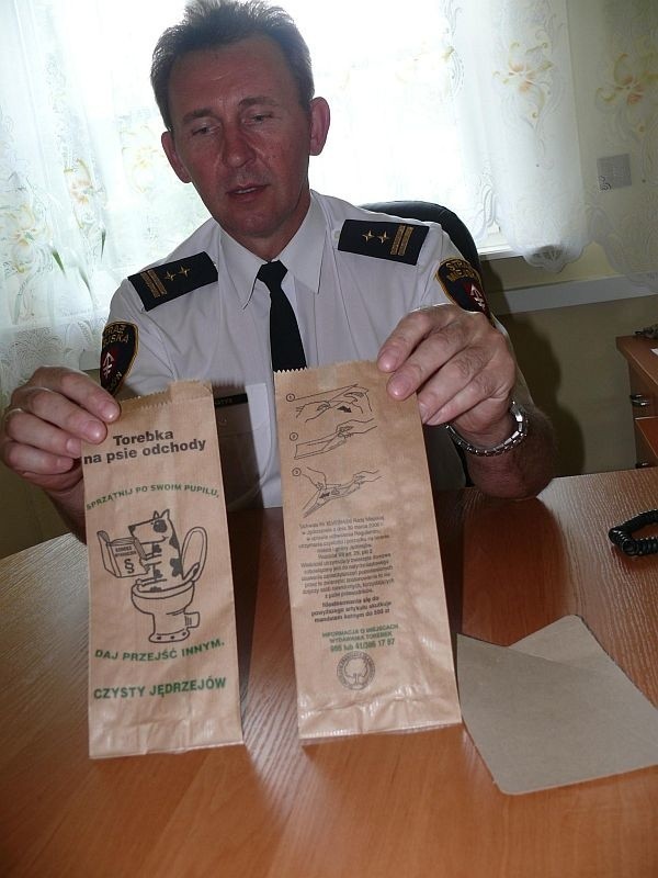 Wojciech Hatys, komendant Straży Miejskiej w Jędrzejowie, prezentuje torebki, które rozdawane będą bezpłatnie właścicielom psów.