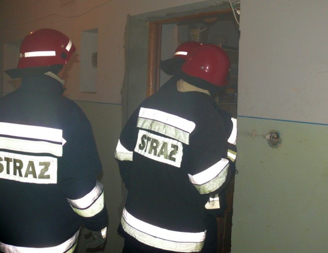 Strażacy wchodzą do mieszkania, gdzie się przypaliło jedzenie.