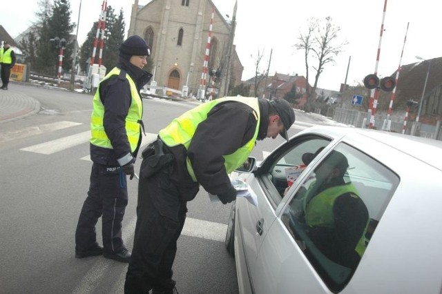 Sierżant Ewa Biegańska z policji i starszy strażnik Ryszard Pawlak wręczają ulotkę kierowcy przed przejazdem kolejowym w Łącznicy koło Starego Kurowa