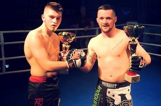 Kacper Miąsko (Grappler Grudziądz - z prawej) w ringu z pucharem za wygraną walkę MMA podczas gali w Mrągowie i ze swoim rywalem