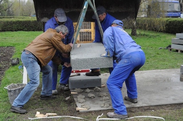 Pracownicy Zakładu Kamieniarskiego Furmanek ustawiają pierwsze płyty granitowe pod cokół pomnika.