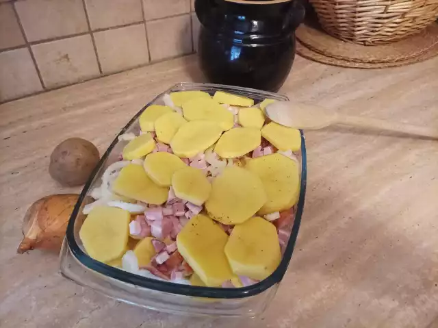 Ziemniaki zapiekane z boczkiem i cebulą to pomysł na niedrogi i dobry obiad. Na zdjęciu ziemniaki przed włożeniem do piekarnika.
