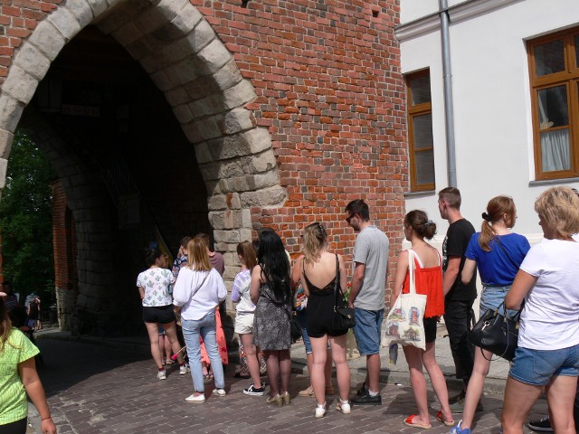 Turyści pamiętają o Sandomierzu. Kolejki do Bramy Opatowskiej, do Podziemnej Trasy Turystycznej, tłumy na zamkowym dziedzińcu. Swoje w kolejce trzeba odstać do lodziarni i po sandomierską zapiekankę. Meleksy pełne turystów. Podobnie jak restauracje i ogródki. W centrum miasta brak wolnych miejsc postojowych, a w starym porcie turystów witają drewniane łodzie i dostojne łabędzie. To znak, że Sandomierz znalazł się na wakacyjnej mapie turystów, którzy w sobotę, 18 lipca, byli widoczni w każdym zakątku sandomierskiej Starówki i na sandomierskich Błoniach.     Na zdjęciu długa kolejka oczekujących na wejście do Bramy Opatowskiej.ZOBACZ WIĘCEJ NA KOLEJNYCH SLAJDACH>>>