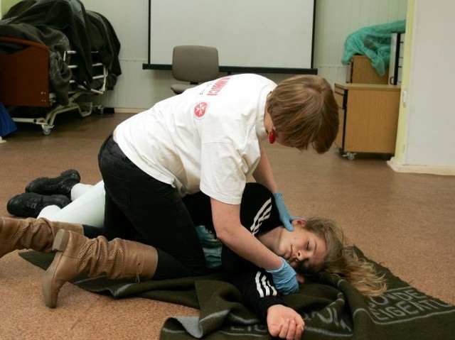 Wolontariuszka ze Stowarzyszenia Joannici w Słupsku pokazuje, jak należy udzielić pierwszej pomocy osobie, która ma atak padaczki.